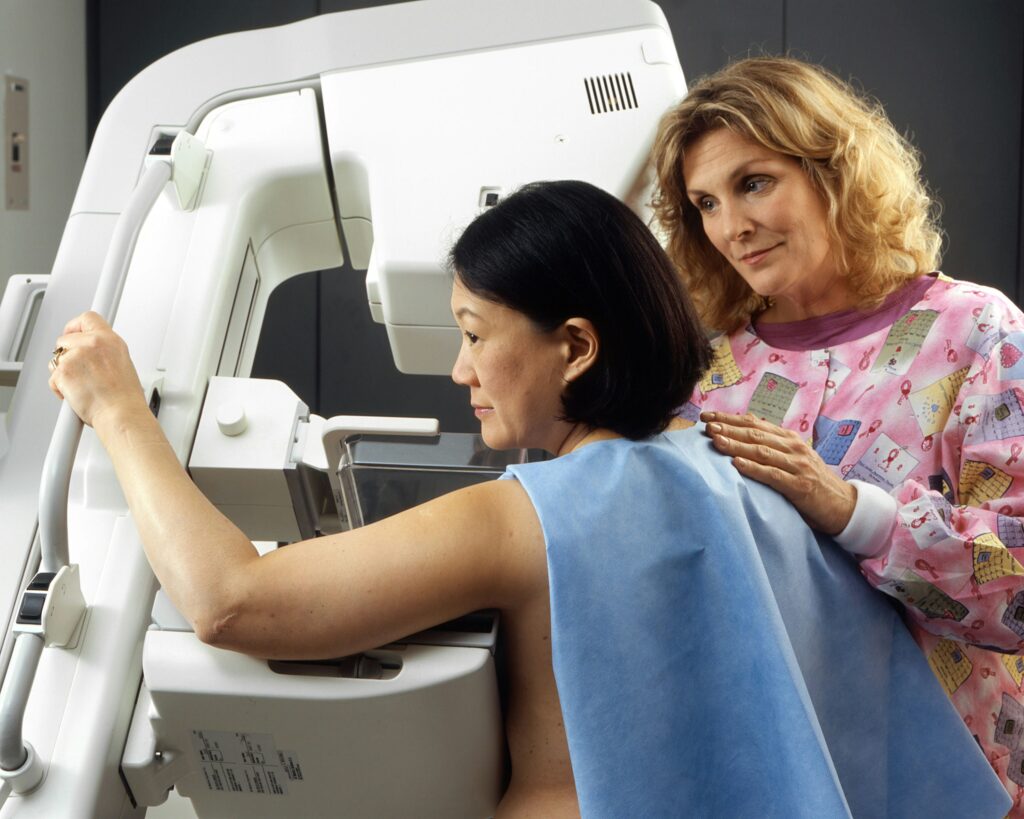 radiology technologist performs a mammogram on a patient